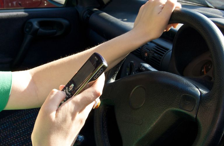 hands of a woman texting while driving